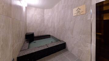 A small, enclosed cold-water bath area with a sign indicating its purpose.