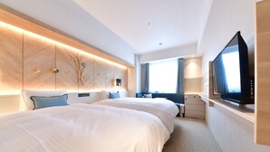 Een moderne hotelkamer met twee grote bedden, een televisie, een zithoek en een groot raam.