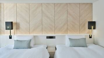 A hotel room with two beds, a wooden panel headboard, bedside lamps, and a control panel.