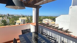 Una terraza con una mesa y sillas, una lámpara colgante y vistas de la ciudad.
