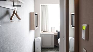 A modern bathroom with a shower, toilet, and sink. There is a towel rack and a mirror on the wall.