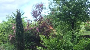 Eine Holzterrasse, die zu einer Steinsäule mit üppigem Grün und blühenden Pflanzen führt.