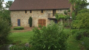 Ein Steinhaus mit geneigtem Dach, einer Holztür und einem kleinen Balkon.