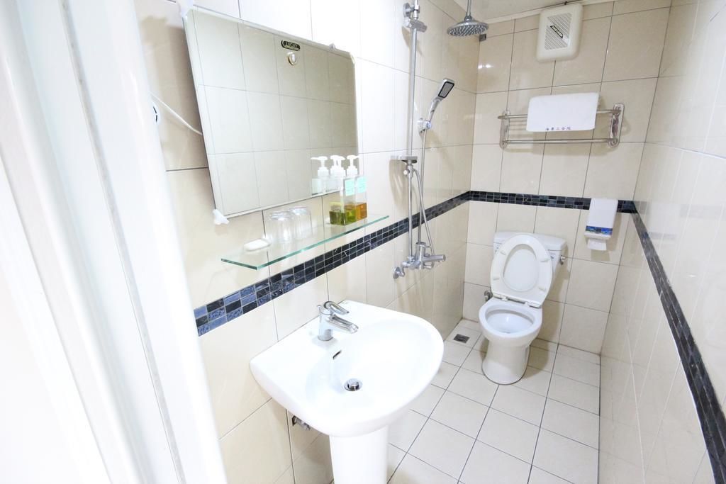 Un baño con lavamanos blanco, inodoro, cabina de ducha de vidrio y espejo.