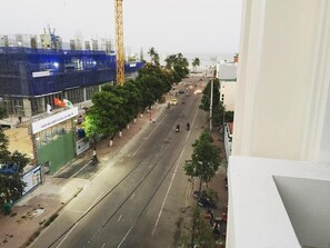 A street view with a construction site on the left, a clear road, and a building with a sign that reads "KHACH SAN LIBERTY CENTRAL".
