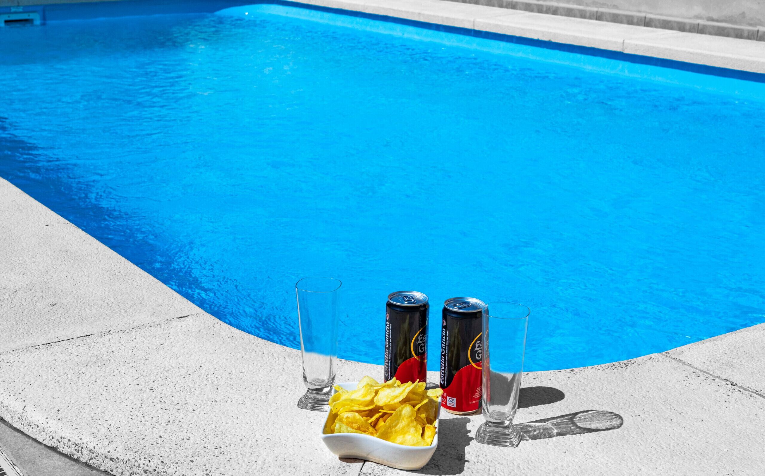 Ein Swimmingpool mit zwei Bierdosen und einer Schüssel Chips am Beckenrand.