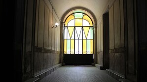 Un couloir se terminant par une grande fenêtre en arc surmontée d’un vitrail.