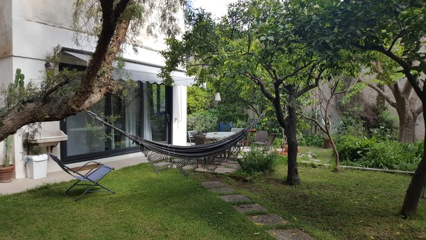 Un jardin avec un hamac, une table de patio et des chaises.