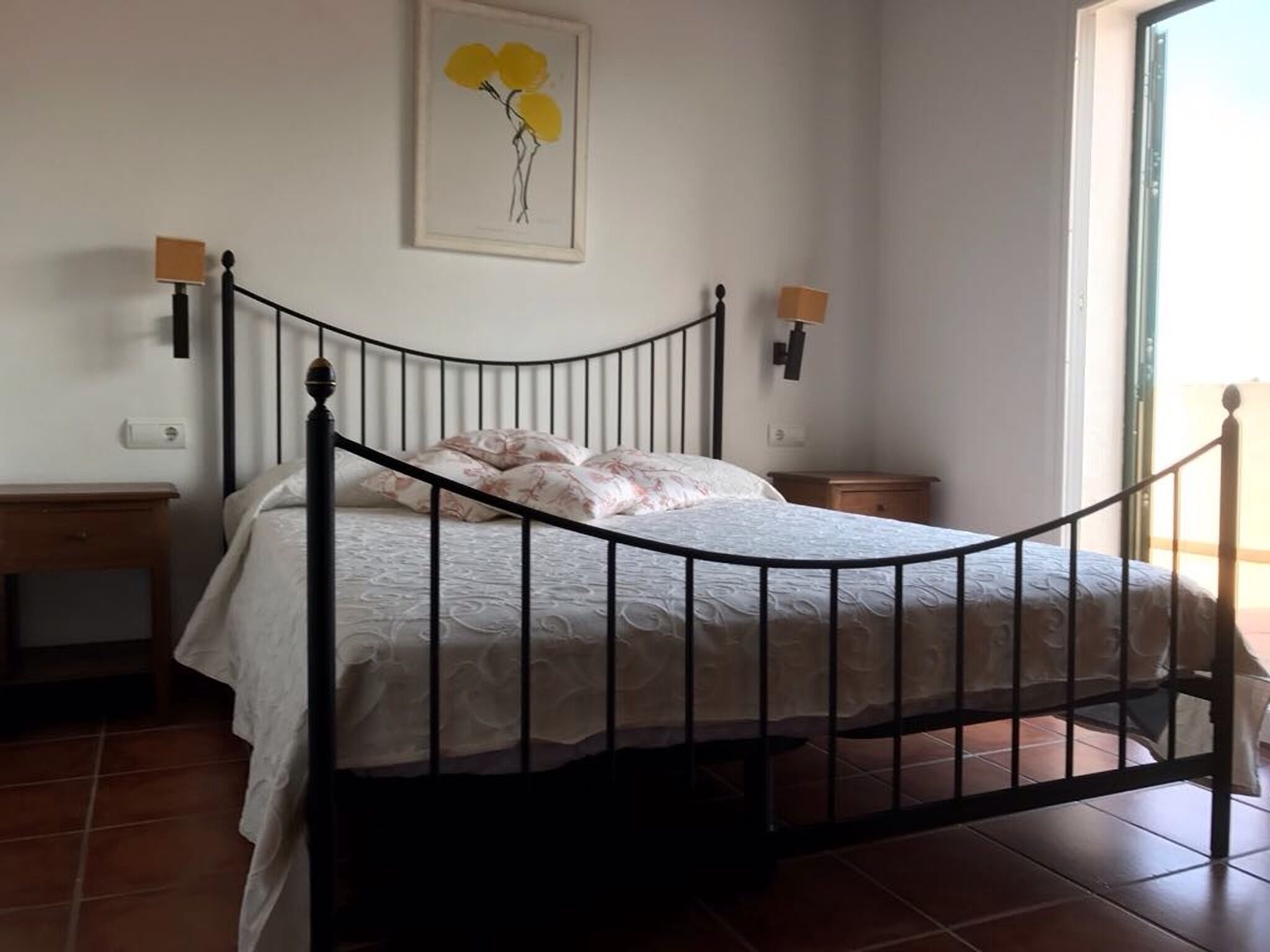A bedroom with a curved bed frame, a nightstand, a bedside table, and a wall-mounted lamp.