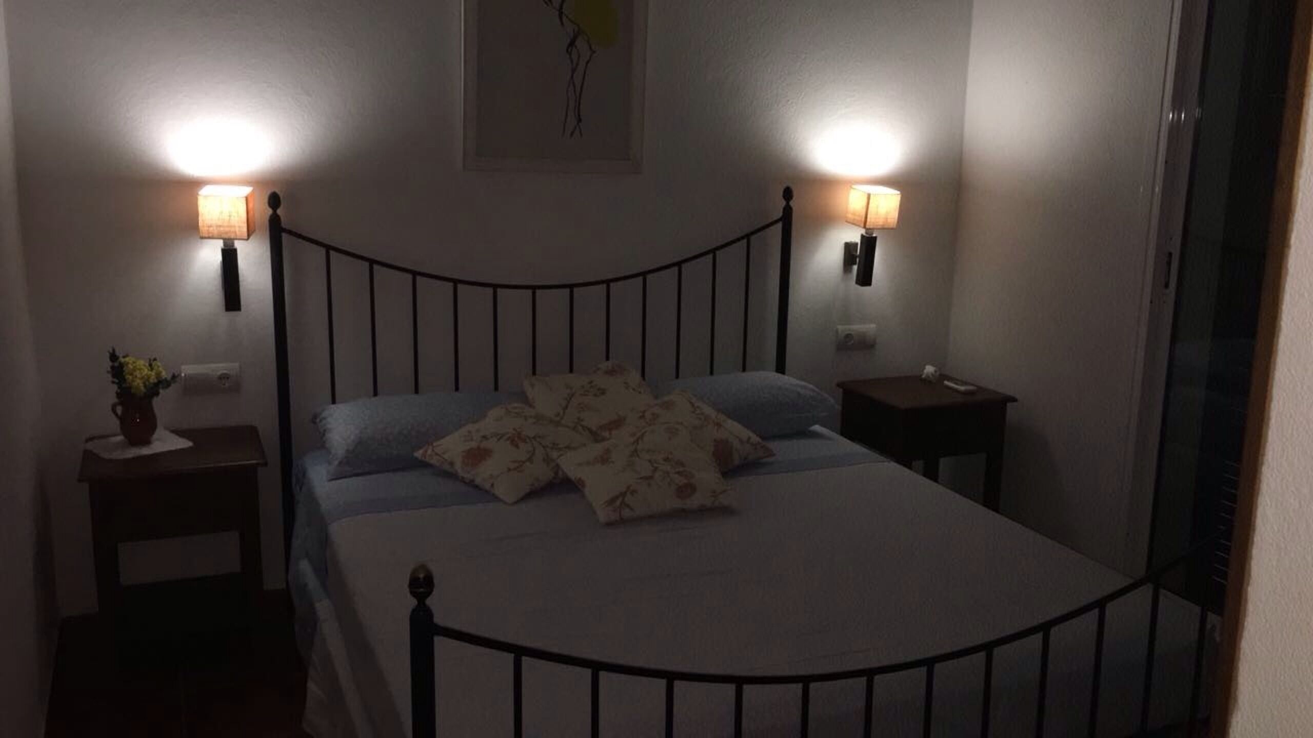 Ein schlafwirtschaftliches Schlafzimmer mit einem Bett, zwei Nachttischen und zwei Wandlampen.