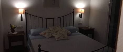 Ein schlafwirtschaftliches Schlafzimmer mit einem Bett, zwei Nachttischen und zwei Wandlampen.