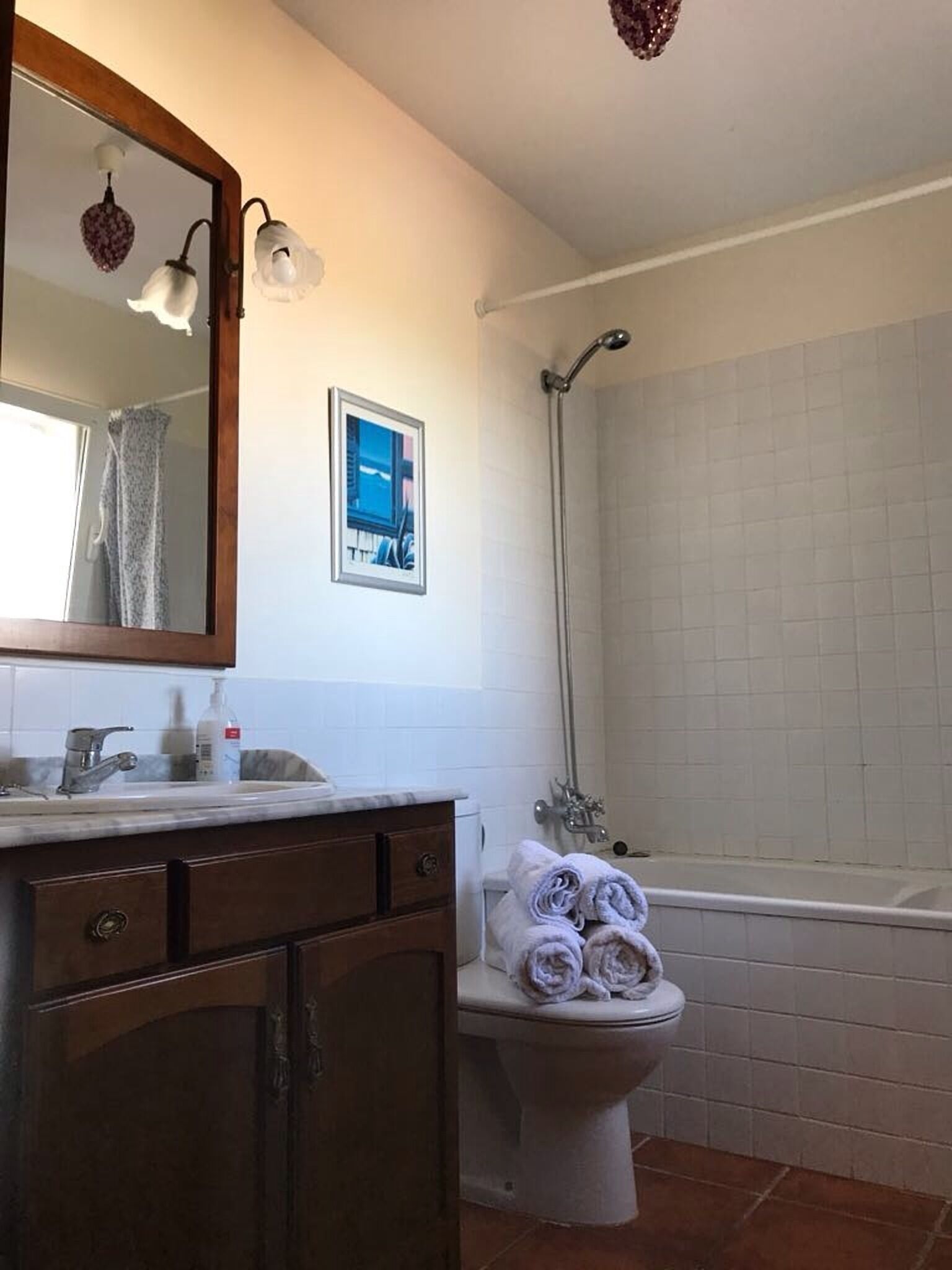 Un baño con lavamanos, espejo, inodoro y ducha.