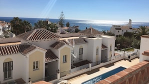 Un quartier résidentiel en bord de mer, avec des bâtiments blancs, une piscine et une vue sur la mer.