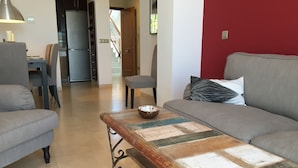 Un salon comprenant un canapé, une table basse et un coin repas avec une table et des chaises.