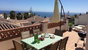 Une terrasse avec une table dressée pour le repas, offrant une vue sur la côte.