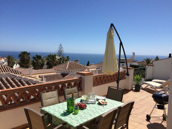 Eine Terrasse mit Esstisch, mit Blick auf die Küste.