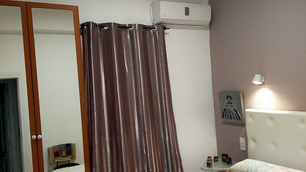 A bedroom with a bed, a mirror, a curtain, an air conditioning unit, a bedside lamp, and a wall-mounted artwork. - apt a5min apie from the beach (Málaga)