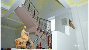 Escadaria com corrimão de metal e parede branca com porta.