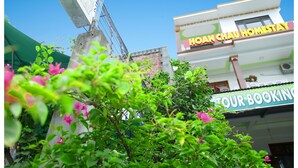 Um edifício com uma placa que diz "HOAN CHAU HOMESTAY" e outra placa que diz "TOUR BOOKING".
