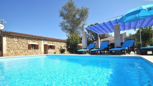 Una piscina cristallina con sdraio e una zona ombreggiata.