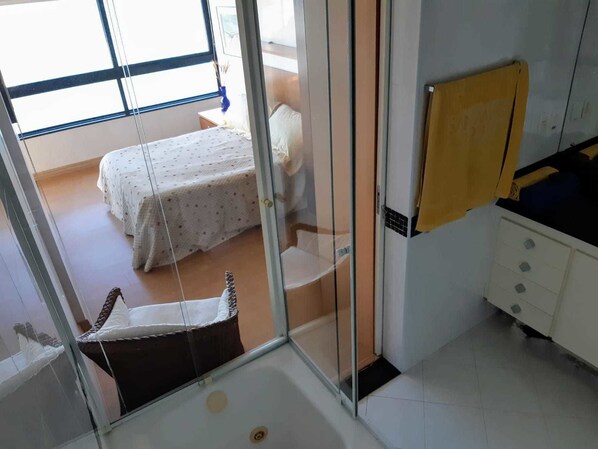 A room with a bed, a shower, and a small bathroom.