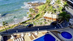 A resort with a pool area, palm trees, and a view of the ocean.