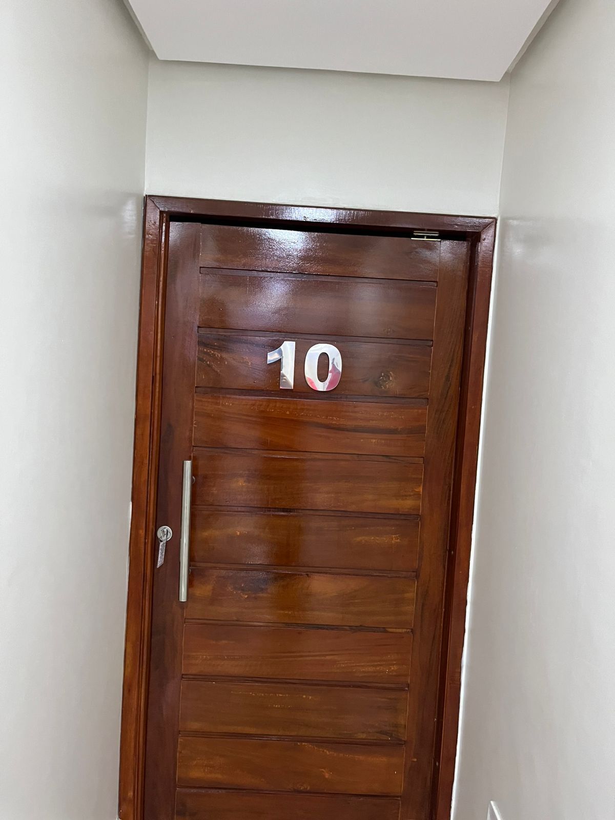 Una puerta de madera con el número 10, un picaporte metálico y una cerradura.