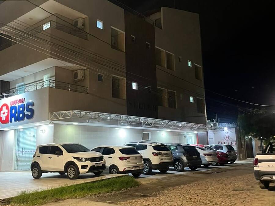 Un edificio de varios pisos con un centro médico en la planta baja, varios coches aparcados y una vista despejada de la calle.