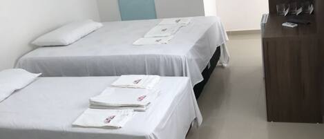 A hotel room with two beds, a desk, and a wardrobe.