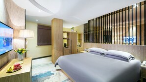 Una habitación de hotel moderna con una cama grande, un televisor de pantalla plana, un escritorio con lámpara y una planta decorativa.