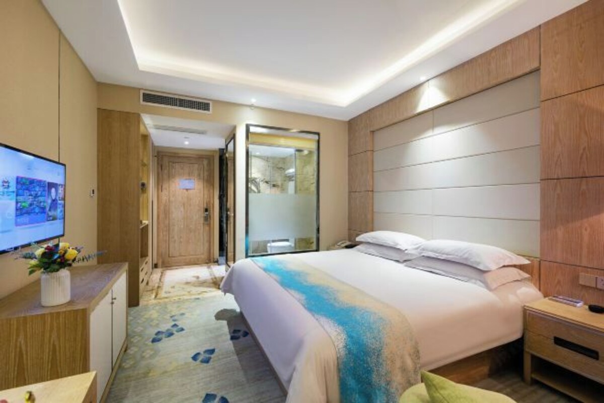 A hotel room with a bed, a TV, a desk, and a bathroom.