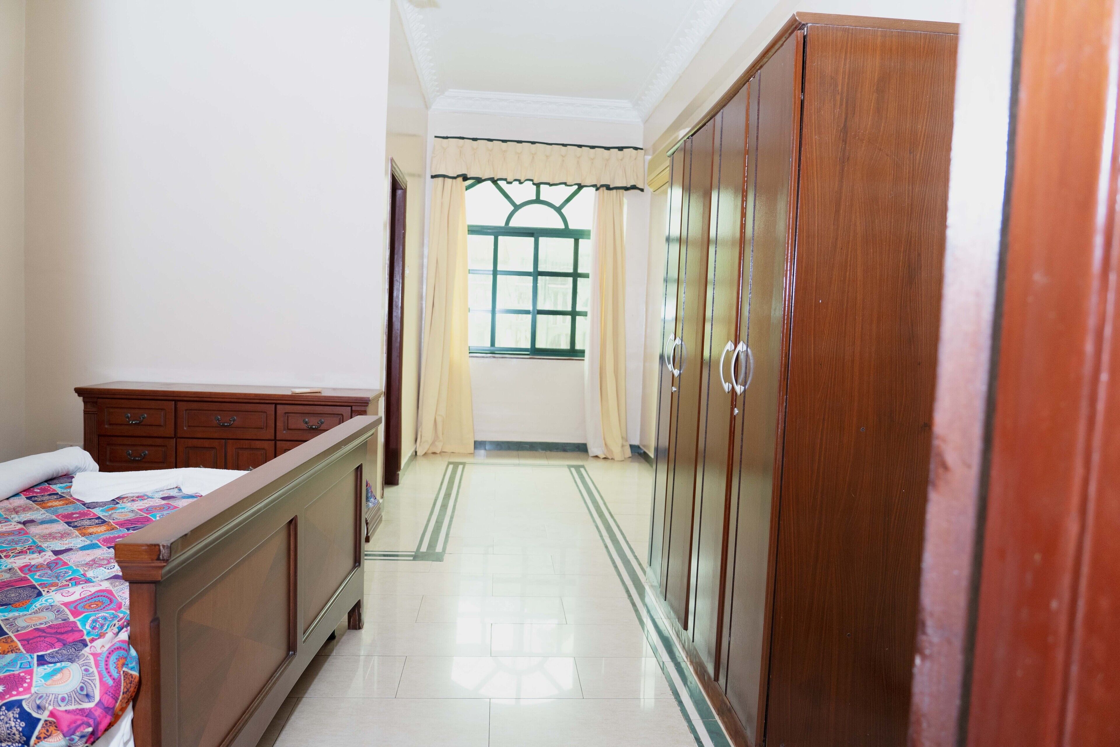 Un dormitorio con cama, armario de madera y ventana con cortinas.