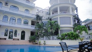 A multi-story hotel with a swimming pool, balconies, and lush greenery. - Luxury Residence with Ocean View in Masaki (Dar es Salaam)