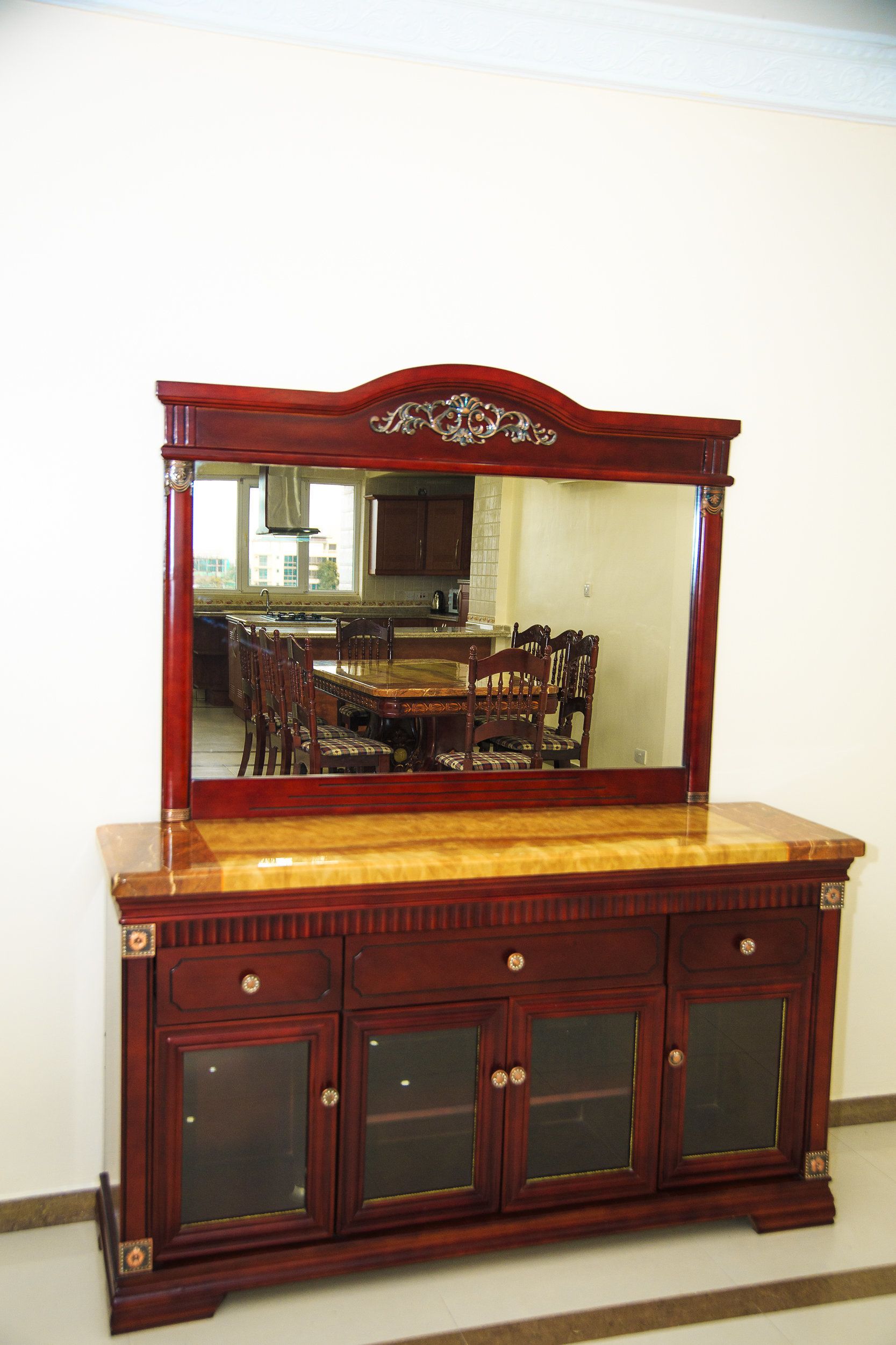 A wooden cabinet with a mirror, drawers, and glass doors.