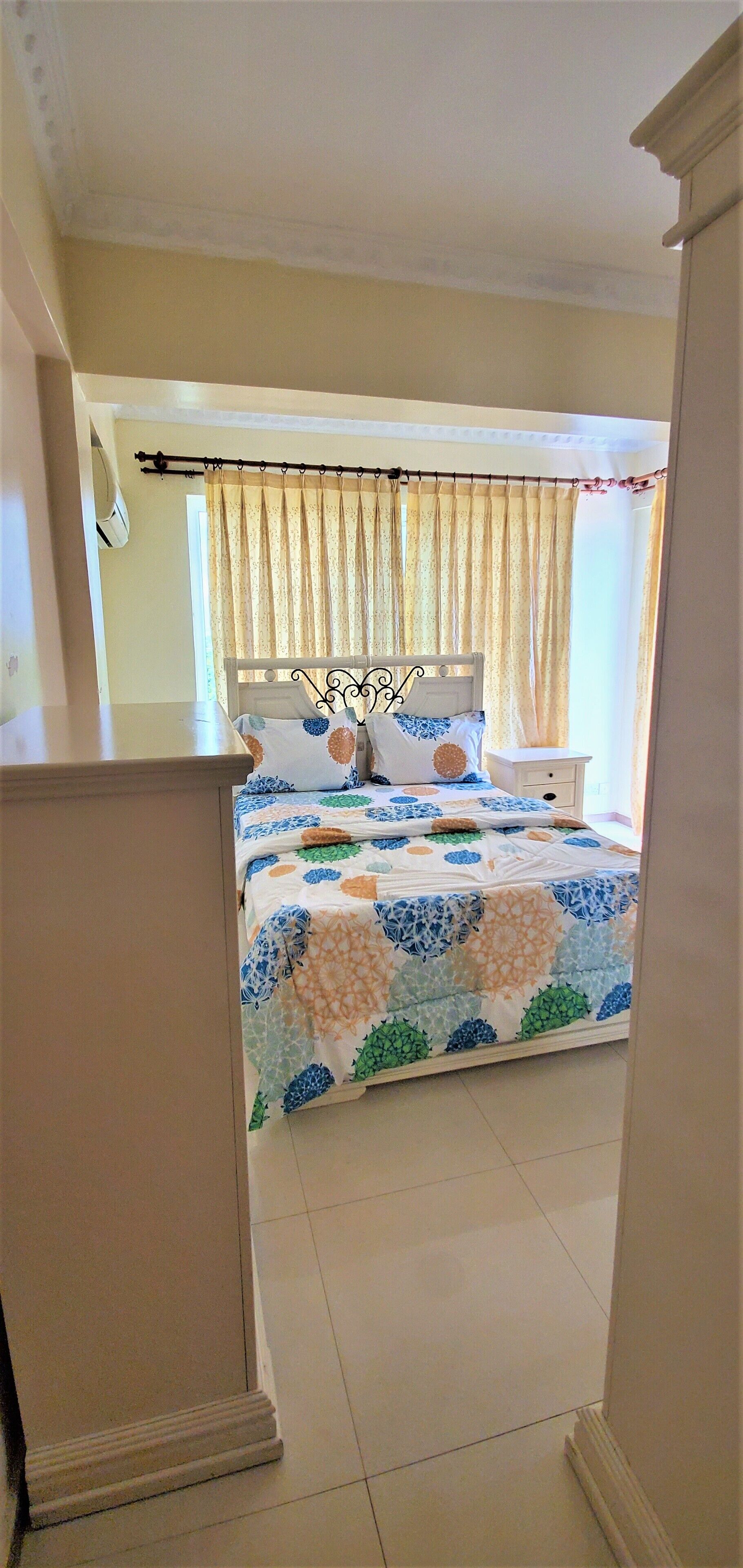 A bedroom with a bed, curtains, a nightstand, and a window.