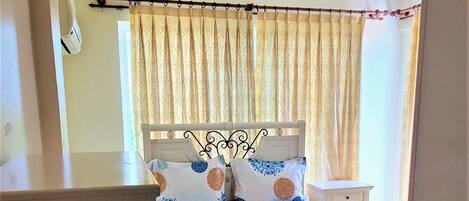 A bedroom with a bed, curtains, a nightstand, and a window.