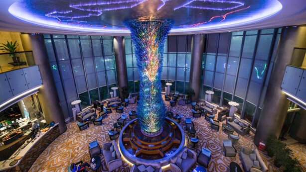 A lobby with a central decorative column, seating areas, and a large windowed wall. - Maya Gleetour Hotel Wuhan (Wuhan)