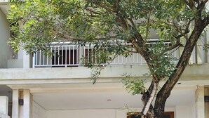 A two-story building with a balcony, a small garden area, and a paved entrance. - Kusuma Homestay Kerobokan (Kerobokan)