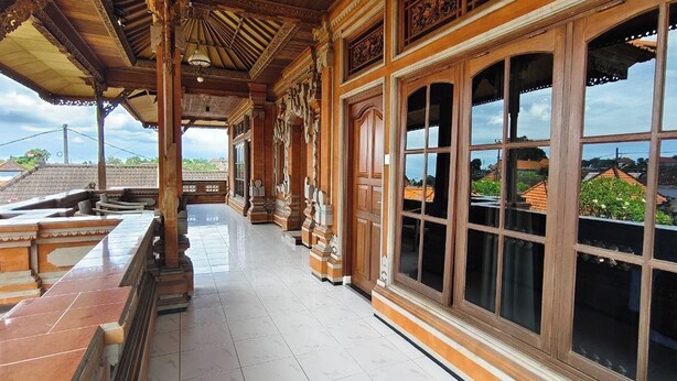 A covered corridor with ornate wooden columns and large windows. - Kusuma Homestay Kerobokan (Kerobokan)