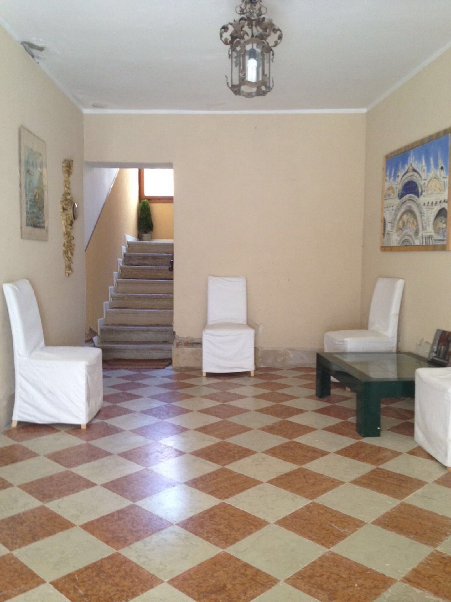 A spacious living area with a checkered floor, a staircase, and a chandelier.