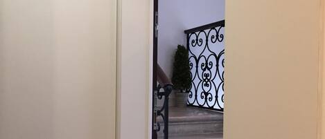 Un corridoio che conduce a una scala con ringhiera in metallo decorata.