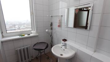 Un baño pequeño con ventana, lavamanos, inodoro y radiador.