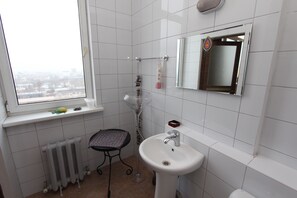 A small bathroom with a window, a sink, a toilet, and a radiator.