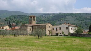 A rural village with stone buildings, a church with a bell tower, and a grassy field. - Villa on the Tuscan hills near Florence (Castelfranco Piandiscò)