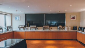 Een moderne keuken met houten kastjes, een groot raam en diverse apparaten.