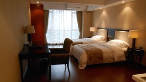 Een hotelkamer met twee bedden, een bureau, een stoel en een raam met gordijnen.