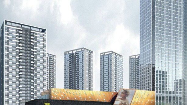 Een modern hoog gebouw met een glazen gevel, omringd door andere hoge gebouwen.