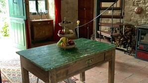 A rustic kitchen with a wooden table, a spiral staircase, and a stone wall. - UNA RARA AVIS - solar house with sea views (Porto do Son (A Coruña))