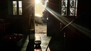 A room with a table, a bottle, and a glass, with sunlight streaming through windows. - UNA RARA AVIS - solar house with sea views (Porto do Son (A Coruña))