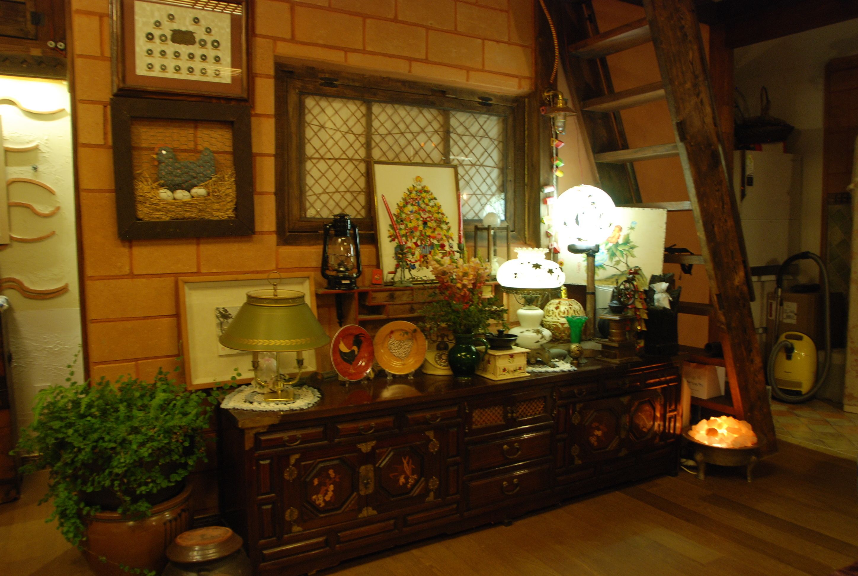 Une commode en bois agrémentée de divers objets décoratifs, notamment une lampe, un vase avec des fleurs et des tableaux encadrés.